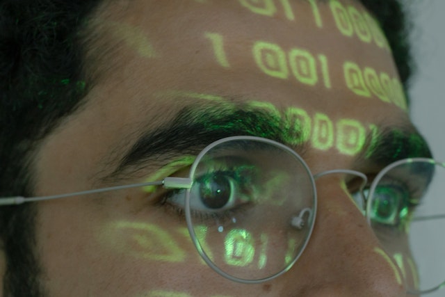 Computer code reflected on a guy
s silver-framed glasses.