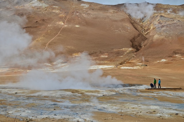 People looking at the steam coming out of the ground in an area with active volcanic activity