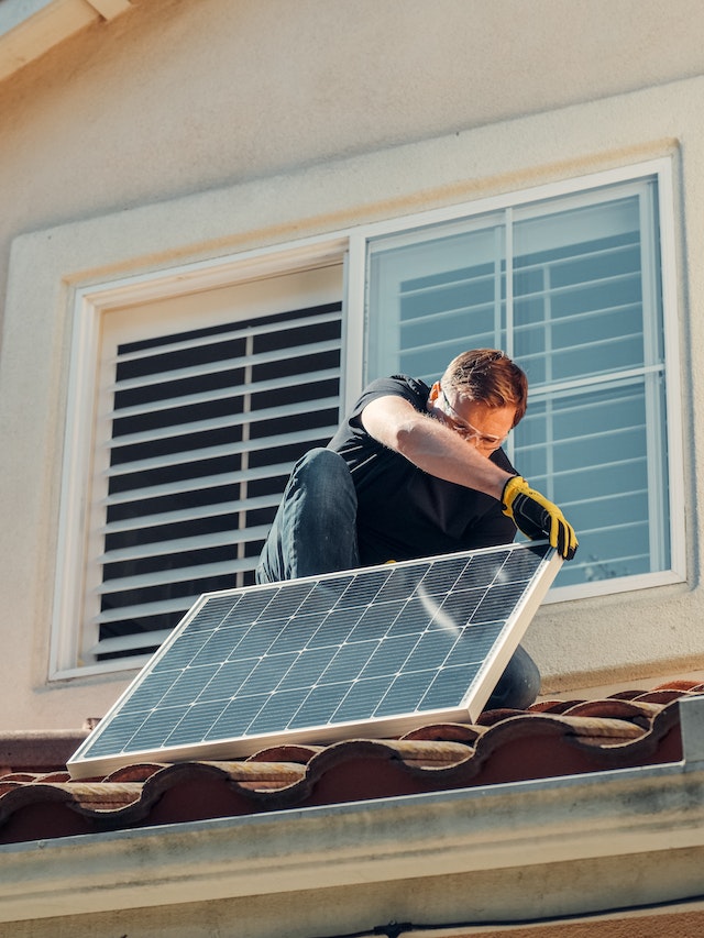 A person installing a solar panel on his roof