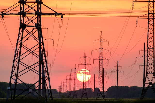 Electrical towers and lines on a field at sunset