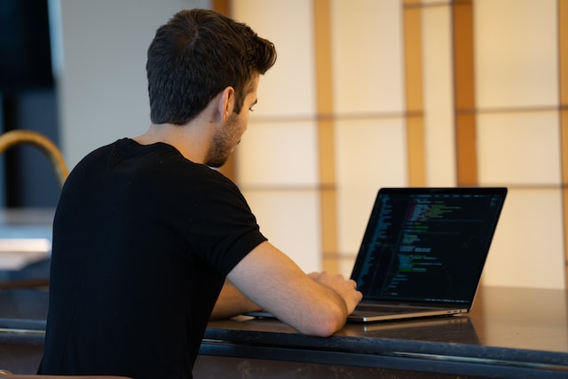 Person in black shirt working on his laptop