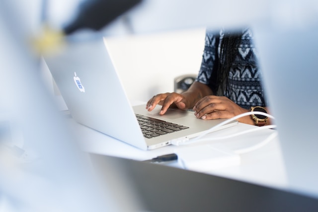 Person typing on a white laptop