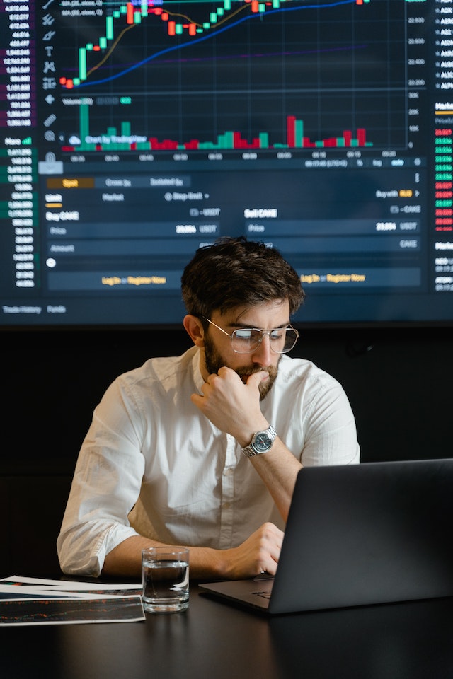 Man in glasses and white shirt analyzing the data on his screen