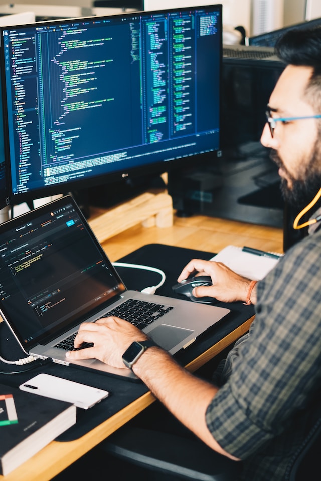 Person working on a laptop with a second monitor on his desk