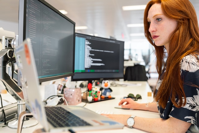 person working on a desktop with a laptop and two monitors